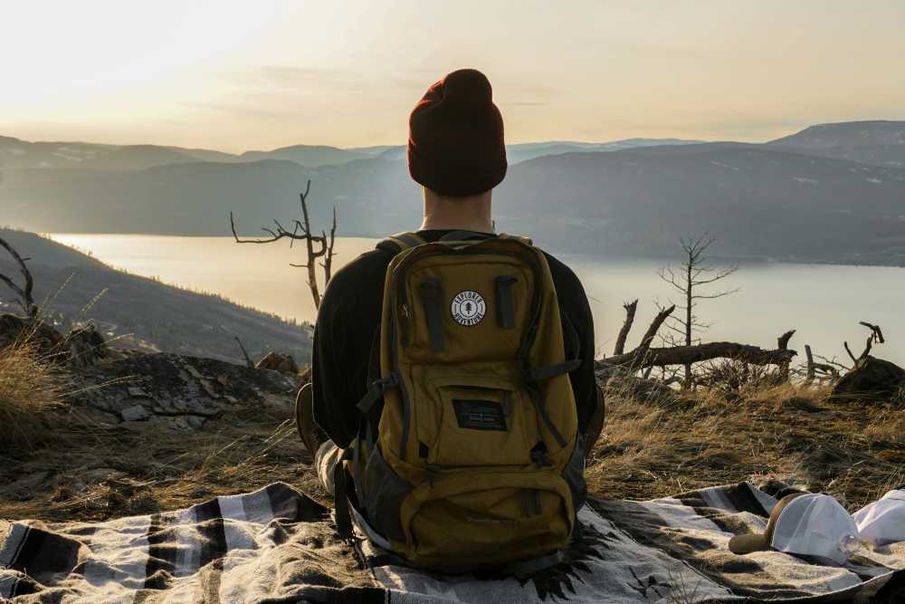 solo traveler with backpack, looking at mountain range, sunrise, wanderlust, adventure, freedom, scenic view