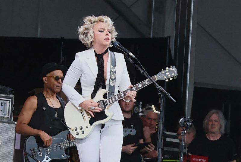 Jazz Fest rain, festival goers in ponchos, muddy field, happy crowd in rain, Louisiana weather, music festival survival, rain boots}