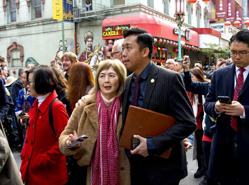 crowds at SF Chinese New Year parade, spectators on sidewalk, bleacher seats, Union Square, parade viewing, families watching}